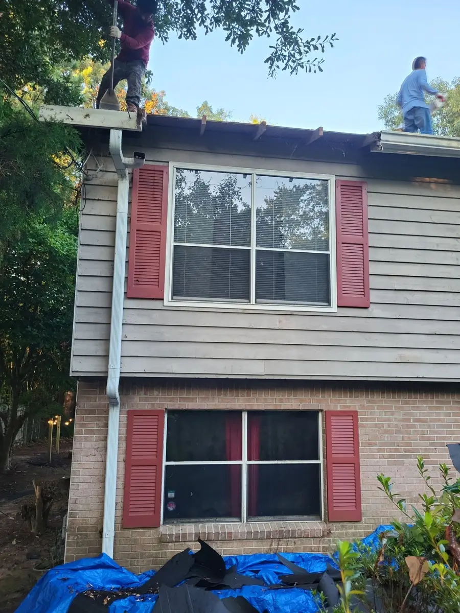 Workers removing roofing materials from house roof above windows, Southern Premier Roofing work near Rest Haven GA