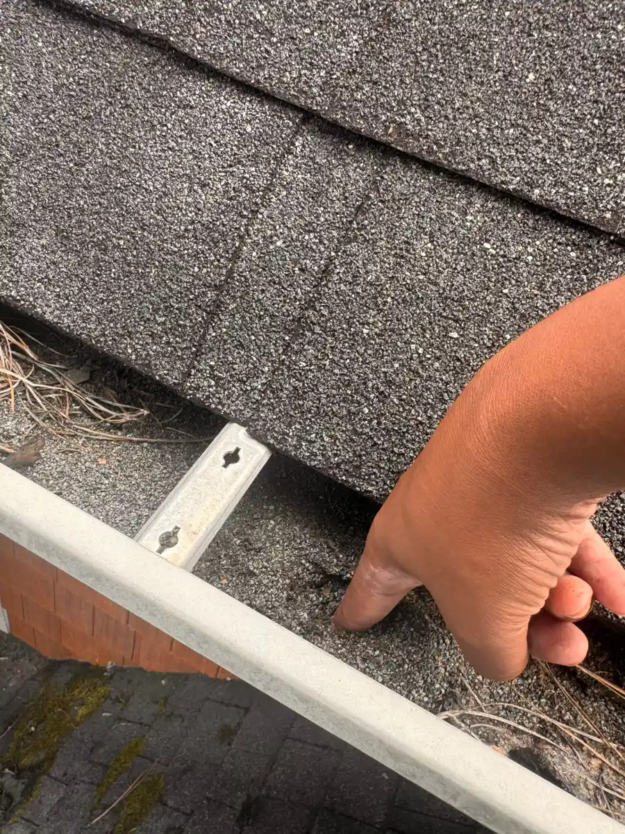 Hand points toward shingle edge and metal flashing detail, Southern Premier Roofing work near Sugar Hill GA