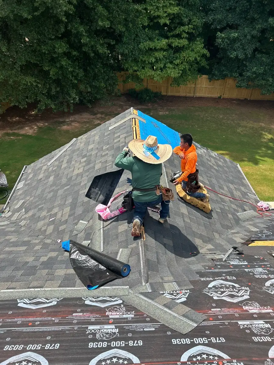 Workers installing shingles and roof materials across steep roof surface, Southern Premier Roofing work near Arcade GA