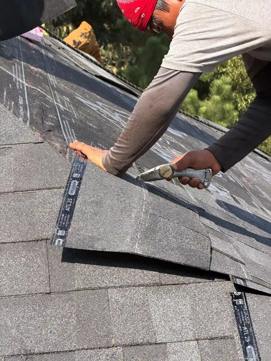 Worker positioning asphalt shingles along sloped roof surface, Southern Premier Roofing work near Auburn GA