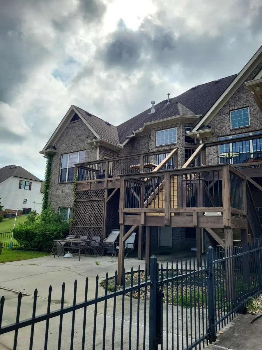 Finished shingle roof above brick townhouse and elevated wooden deck, Southern Premier Roofing work near Colbert GA