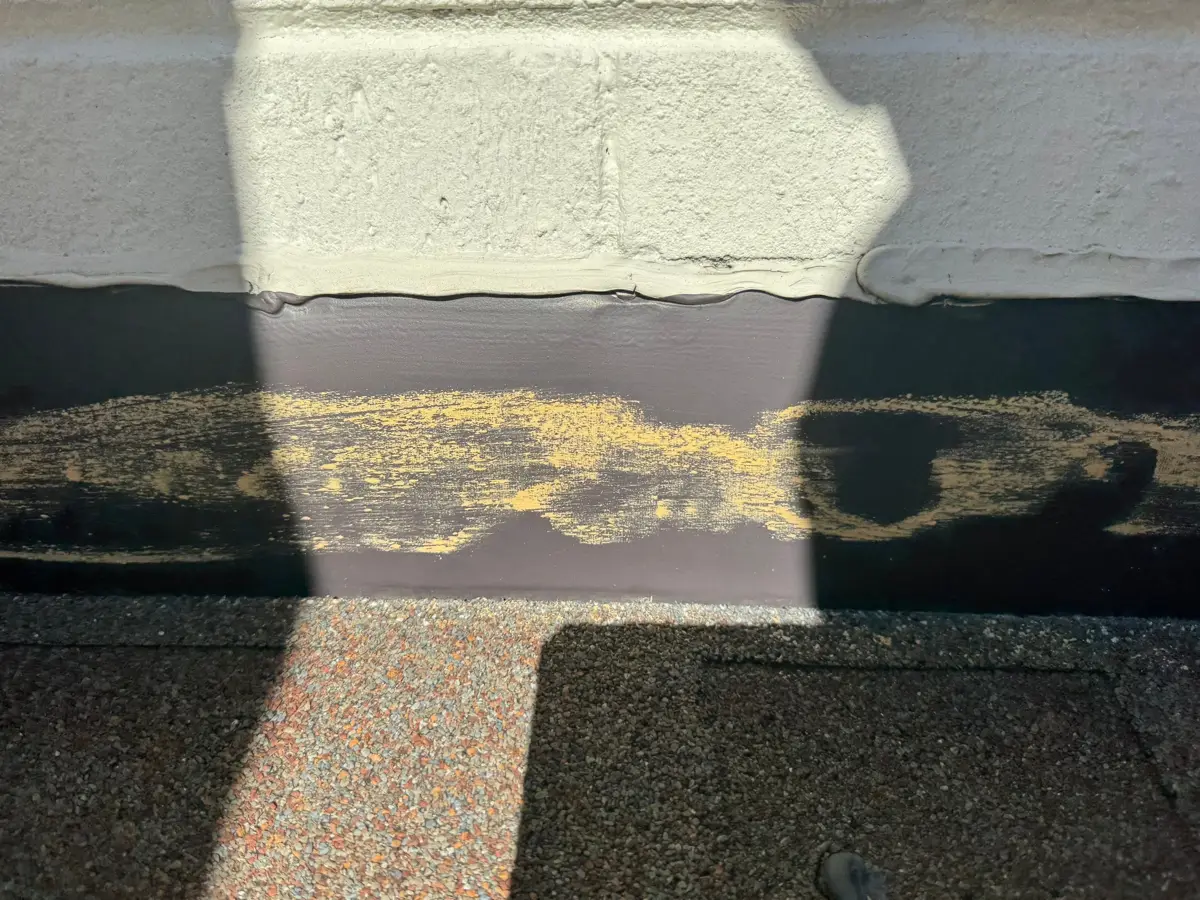 Closeup of roof flashing beneath stucco wall with sealant, Southern Premier Roofing work near Covington GA