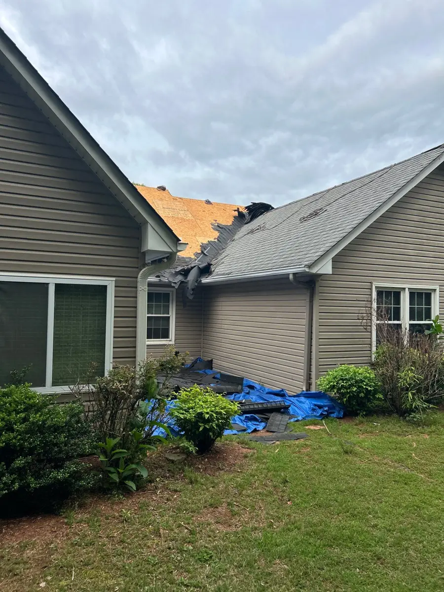 Roof replacement underway with exposed underlayment and covered landscaping, Southern Premier Roofing work near Dacula GA