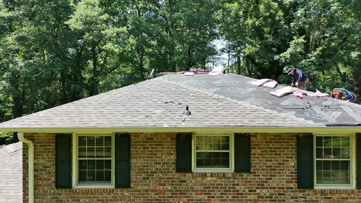 Completed shingle roof covering brick house with surrounding trees, Southern Premier Roofing work near Duluth GA