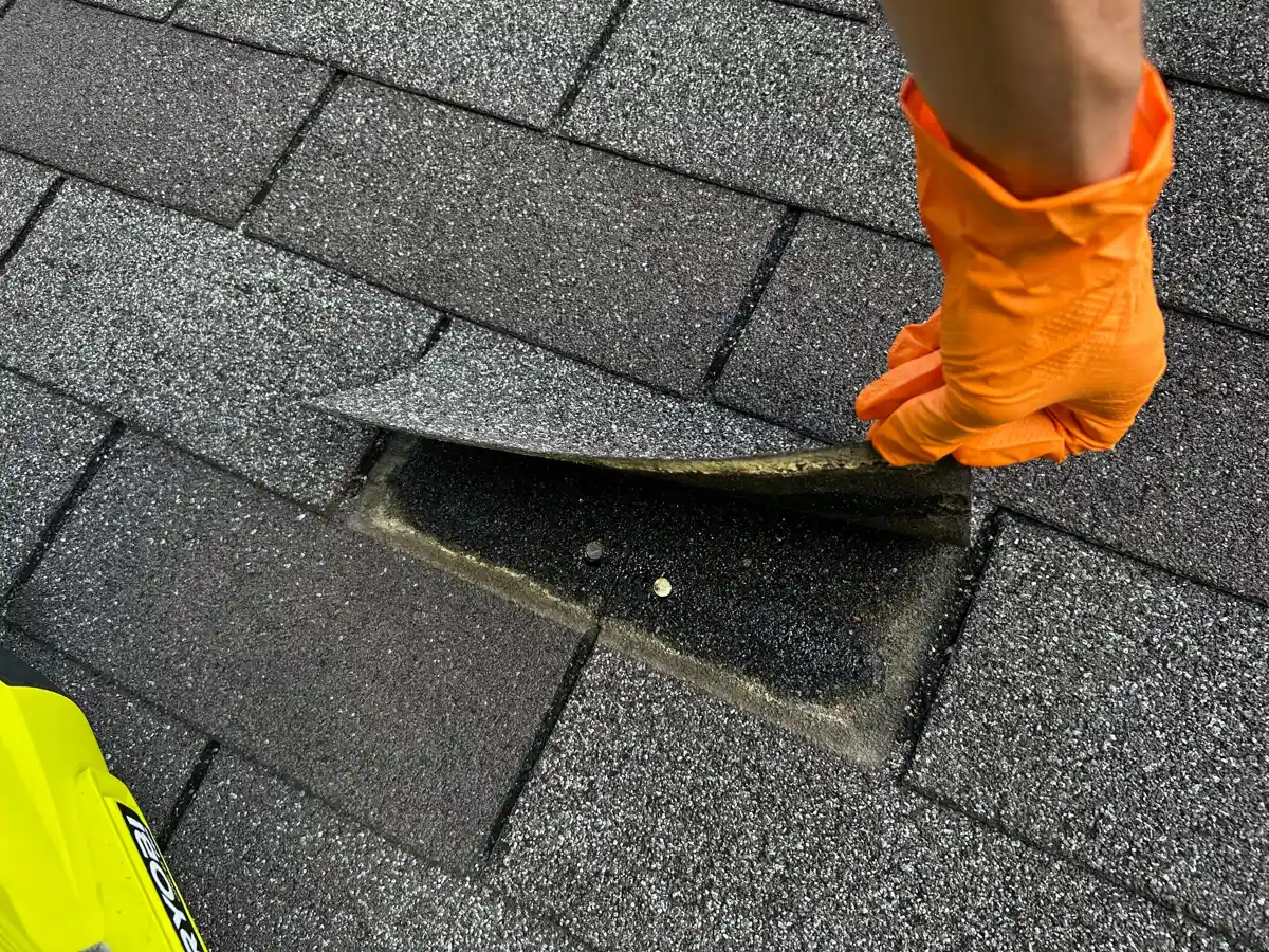Worker lifts shingles to expose roof flashing detail beneath, Southern Premier Roofing work near Flowery Branch GA