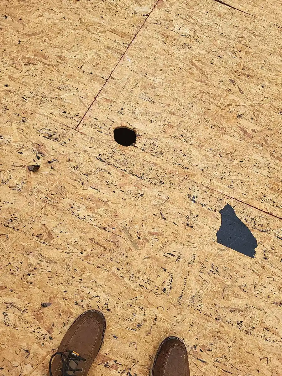 Close view of damaged plywood decking with holes and debris, Southern Premier Roofing work near Gillsville GA