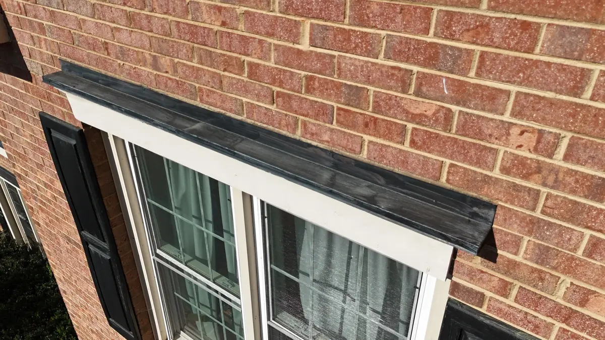 Black metal flashing installed above brick wall and window trim, Southern Premier Roofing work near Gillsville GA