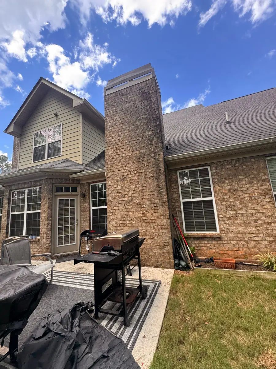 Completed shingle roof with brick chimney and backyard patio, Southern Premier Roofing work near Gillsville GA