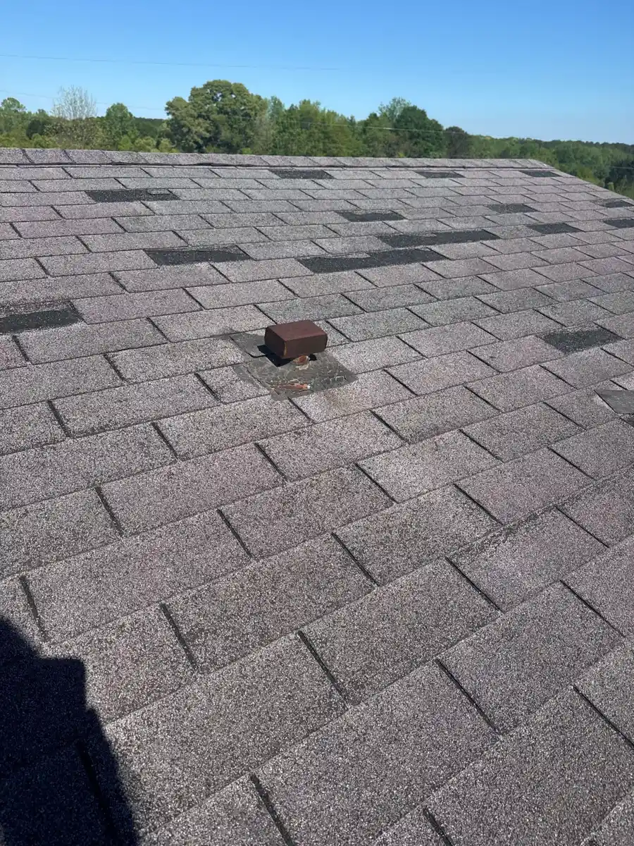 Roof shingles show several dark rectangular patches and a raised vent, Southern Premier Roofing work near Johns Creek GA