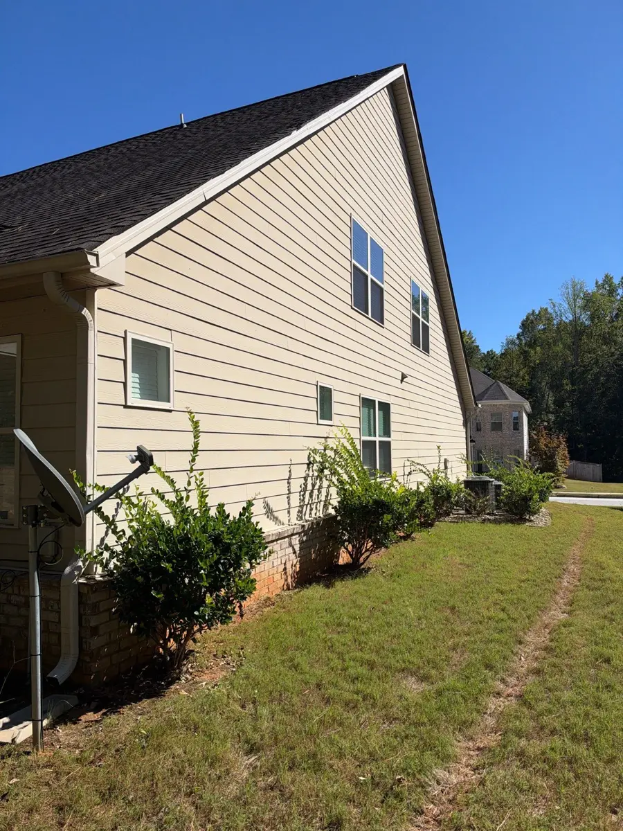 Wide house gable with shingled roof, windows, lawn, and shrubs, Southern Premier Roofing work near Lithonia GA
