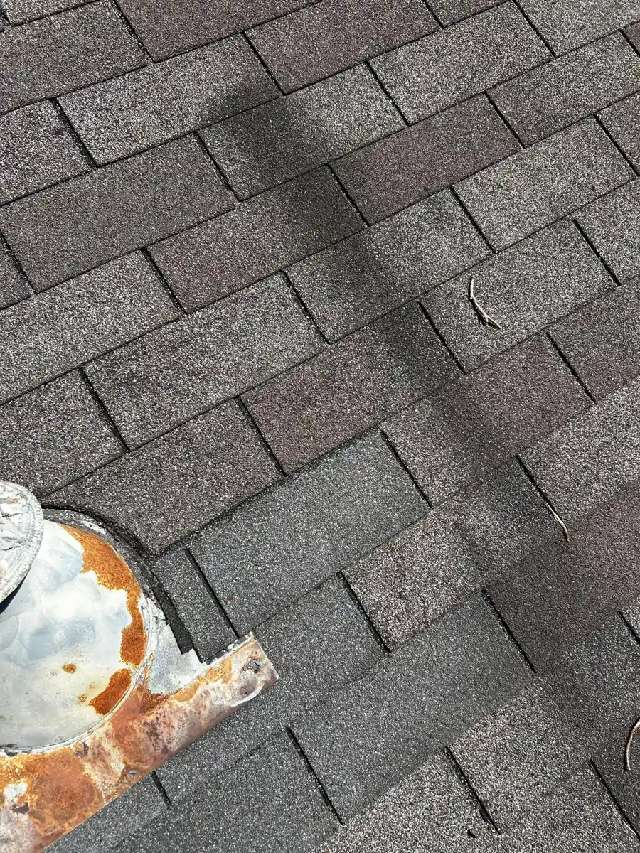 Shingles show patchy discoloration and a damaged roof fixture, Southern Premier Roofing work near Maysville GA