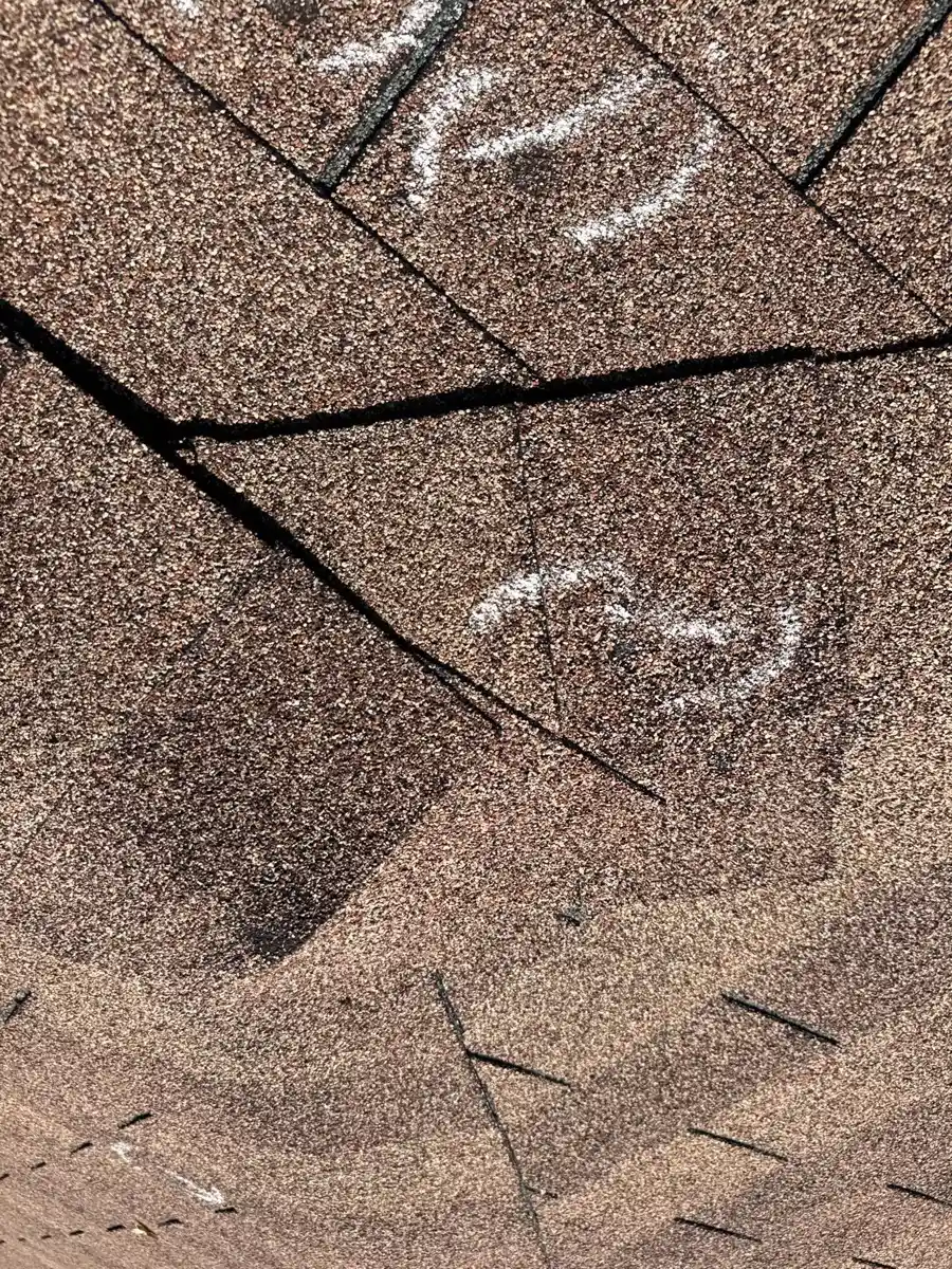 Close view of cracked roofing shingles with marked damage, Southern Premier Roofing work near Oakwood GA