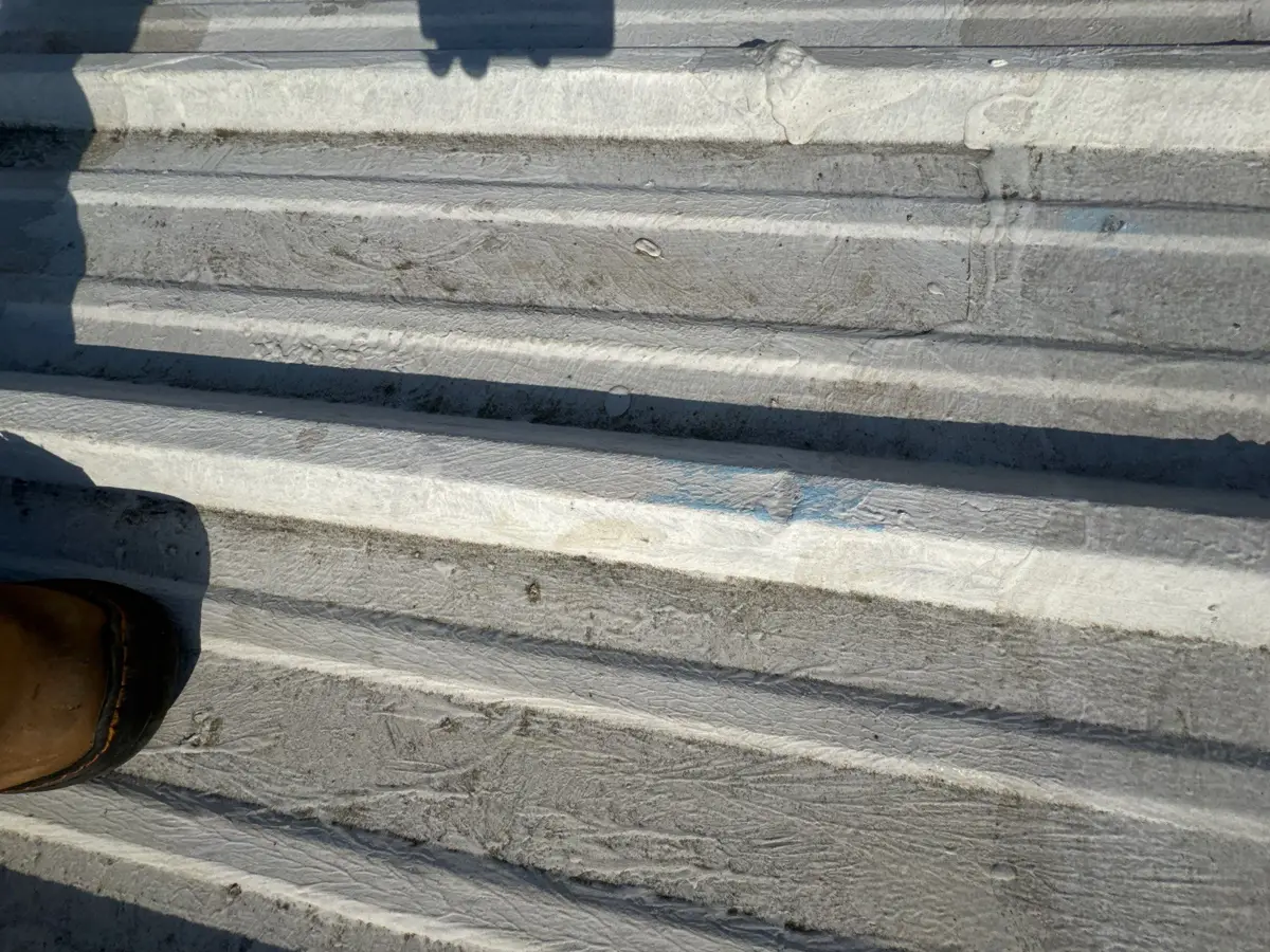 Close view of worn corrugated roofing with dirt and surface damage, Southern Premier Roofing work near Rest Haven GA