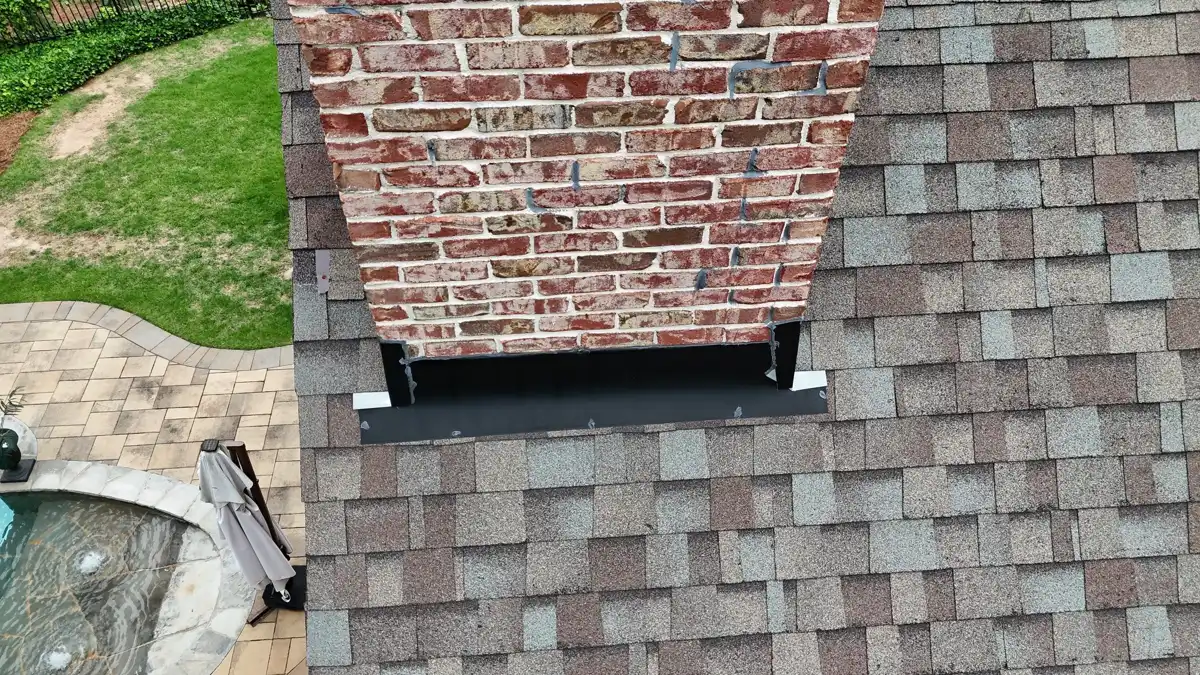 Roof shingles surround brick chimney with visible metal flashing detail, Southern Premier Roofing work near Rutledge GA