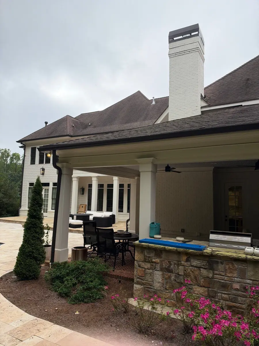 Completed brown shingle roof above covered patio and stone facade, Southern Premier Roofing work near Statham GA