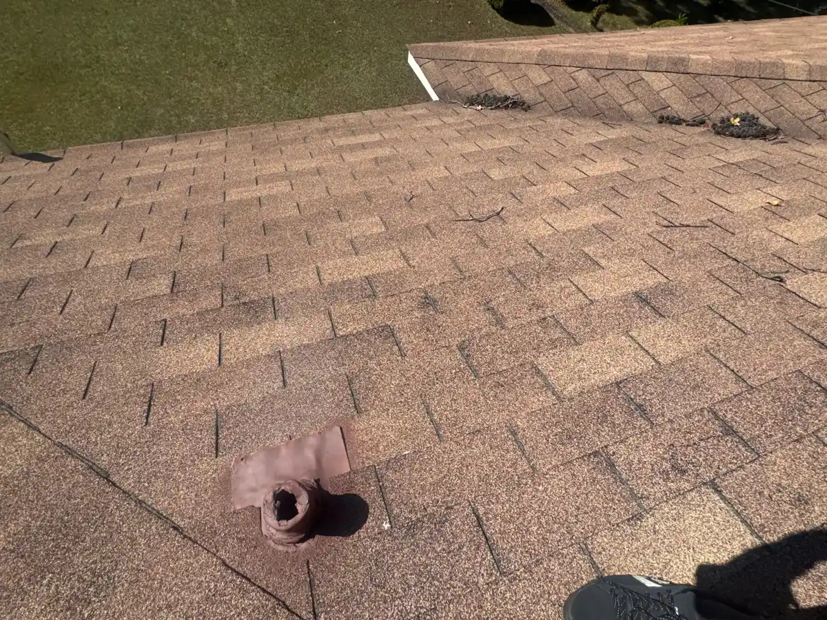 Roof shingles contain a small circular damaged opening near ridge, Southern Premier Roofing work near Tucker GA