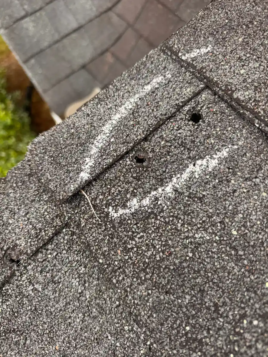 Close-up shows lifted shingles and exposed fasteners near roof joint, Southern Premier Roofing work near Watkinsville GA