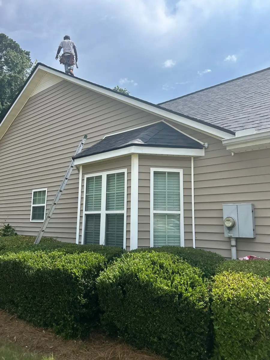 Completed shingles visible above dormer, siding, and landscaped shrubs, Southern Premier Roofing work near Braselton GA