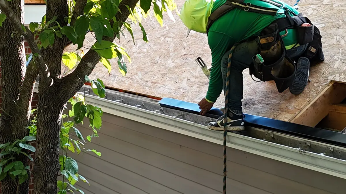 Worker handling roof edge flashing beside tree and siding, Southern Premier Roofing work near Winder GA